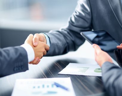 Two people in suits shaking hands regarding a financial or business agreement