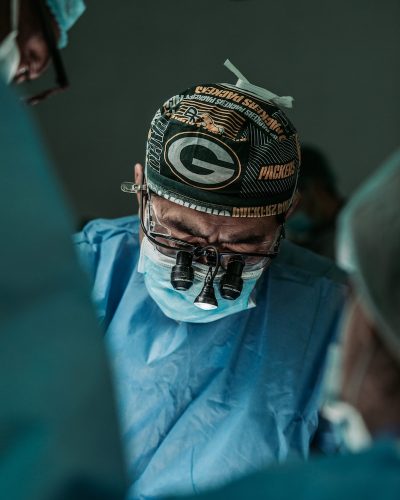 Doctor performing surgery wearing Green Bay Packers hat